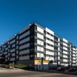 El edificio proyectado se implanta en el terreno ajustándose escrupulosamente a lo estipulado en el Plan Parcial, que continúa el ritmo de manzanas cerradas o semicerradas de todo el área, ya configurada, alineándose a las calles.